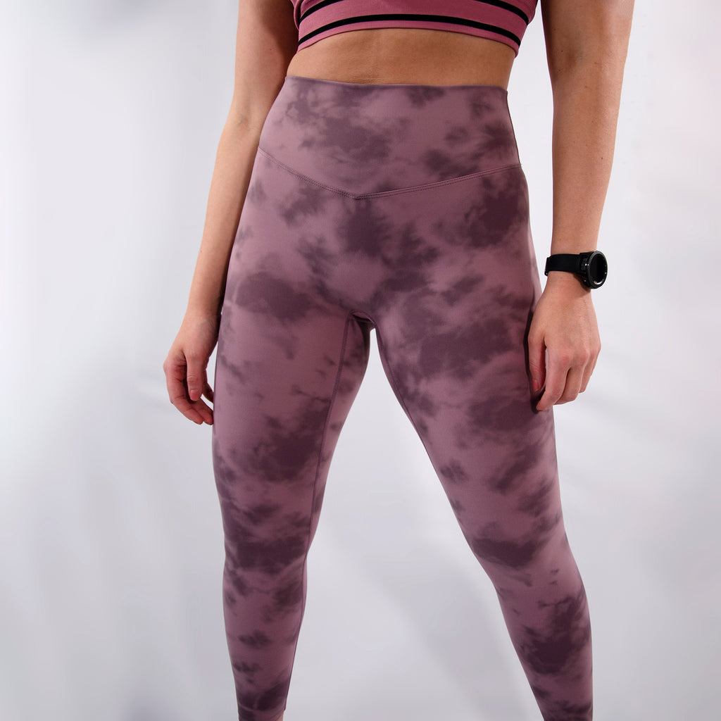 Woman wearing body contouring gym leggings with tie dye textured design in purple colour